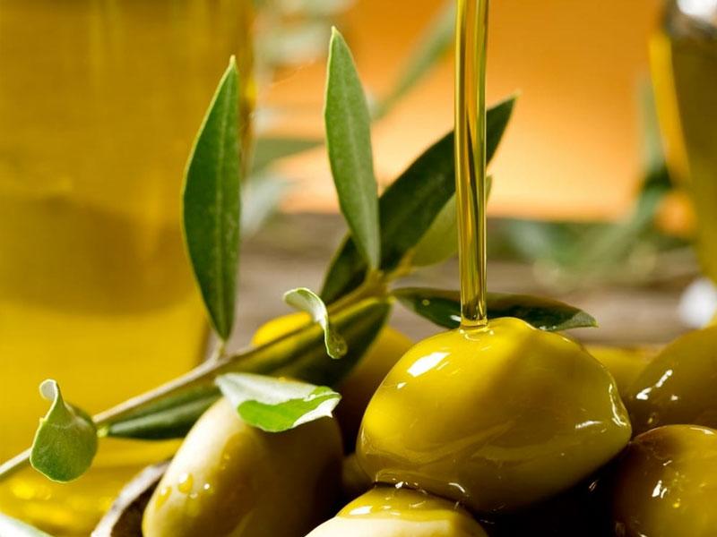 Olive verdi con olio d'oliva che scorre, foglie di ulivo in vista.